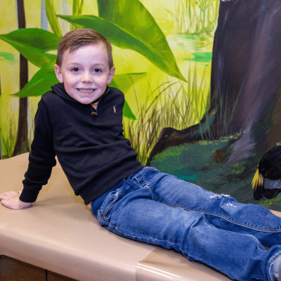 Little boy sitting down, smiling, showing good oral health