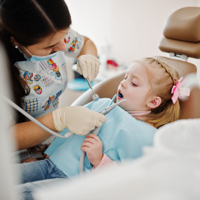 The Connection Between Oral Health in Children and Overall Health 10 Little girl getting her teeth worked on at the dentist, representing oral health in children