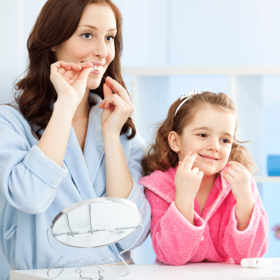 Fun Ways to Teach Dental Hygiene for Kids 8 a woman and a girl flossing their teeth, representing dental hygiene for kids