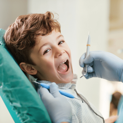 The Importance of Dental Sealants for Kids in Cavity Prevention 6 a child sitting in a chair with his mouth open, representing dental sealants for kids